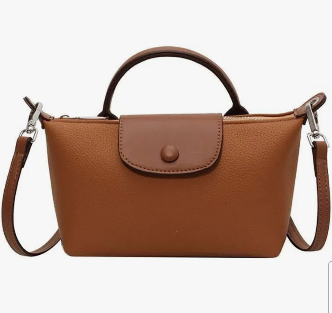 NCHIMBA tan pebble-textured vegan leather mini top handle crossbody bag with a flap closure and adjustable strap.