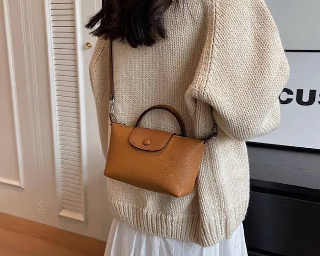 NCHIMBA tan pebble-textured vegan leather mini crossbody bag with top handle worn over a beige knit sweater
